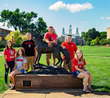 Six of the 2018 Coyote Legacy Scholarship recipients pose with the Legacy statue on USD's campus.