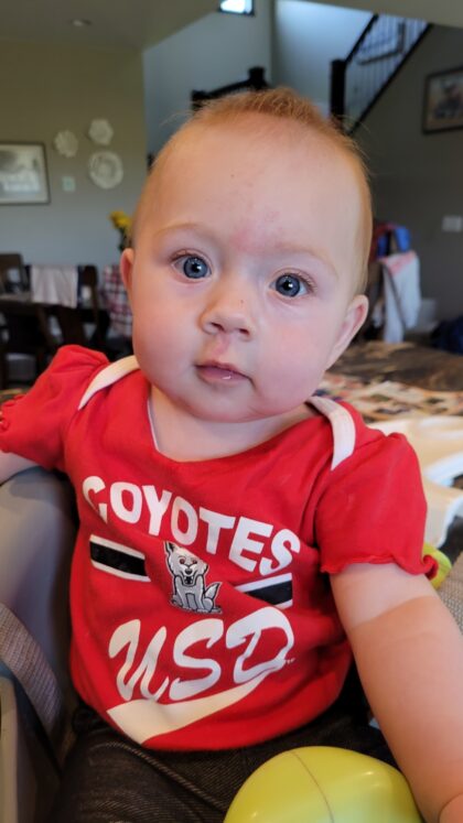 A baby in a USD Coyote shirt