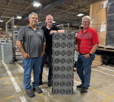 Kieth Thomas and his partners standing next to a computer server.
