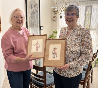 Sandra Percy and Carol Geu holding donated Oscar Howe paintings.